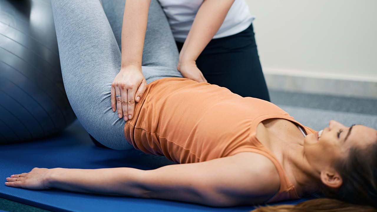 Happy female physiotherapist working with young woman health club.